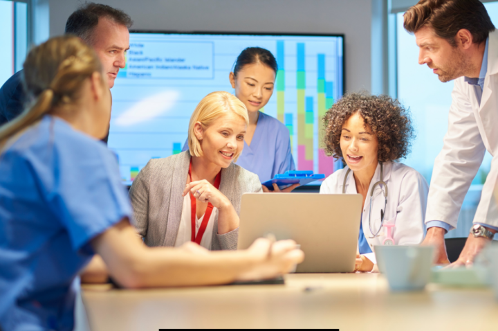 medical or scientific team looking at a computer screen around a desk